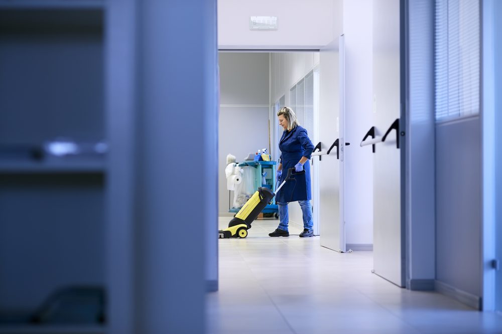 Operatrice So.Ge.Pa. al lavoro con il carrello delle pulizie nel corridoio di un ufficio